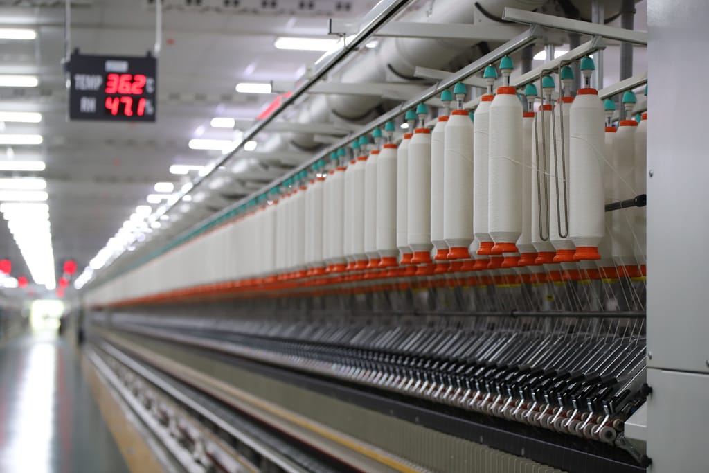 Rows of yarn bobbins running on a spinning machine in a textile mill