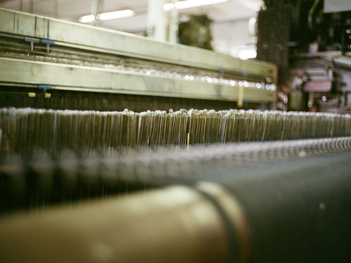 Close view of threads running under tension through an industrial weaving loom